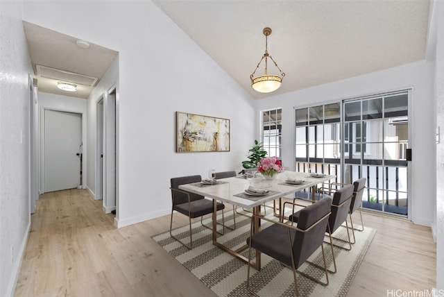 dining room featuring light wood-type flooring, lofted ceiling, plenty of natural light, and baseboards