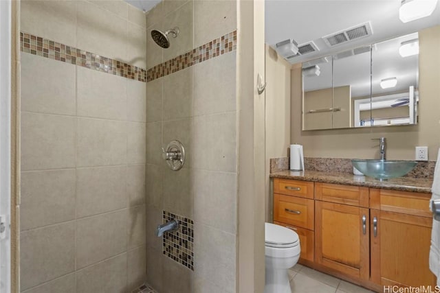 bathroom featuring visible vents, tiled shower, toilet, tile patterned floors, and vanity