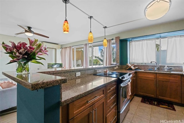 kitchen featuring dark stone counters, decorative light fixtures, a sink, and stainless steel electric stove