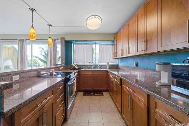 kitchen with light tile patterned floors, a sink, stainless steel electric range, brown cabinetry, and decorative light fixtures