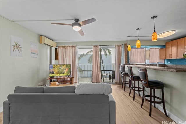 living area with a wall unit AC, light wood-type flooring, and a ceiling fan