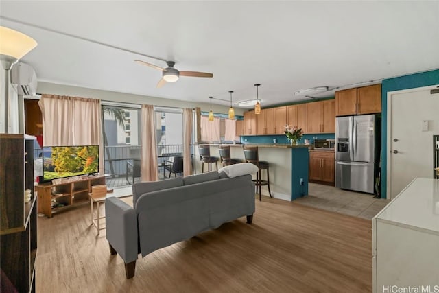 living area featuring light wood-style floors, a wall unit AC, and ceiling fan