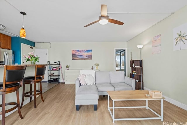 living area with ceiling fan, light wood-style flooring, and baseboards