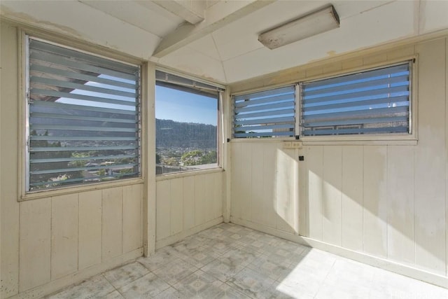 unfurnished sunroom featuring vaulted ceiling with beams