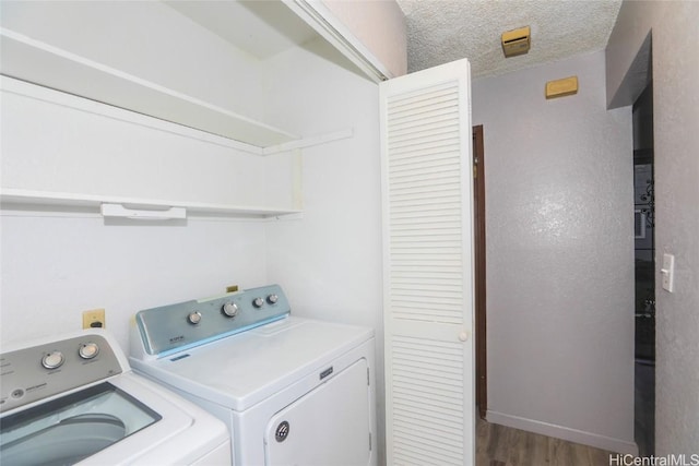 washroom with a textured ceiling, laundry area, wood finished floors, baseboards, and independent washer and dryer