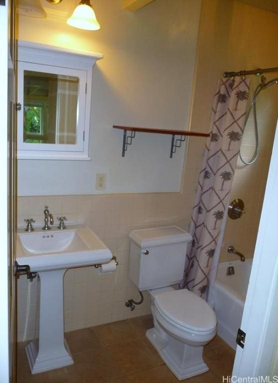 bathroom with tile patterned floors, toilet, tile walls, shower / tub combo, and wainscoting