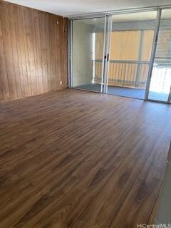 unfurnished room featuring wooden walls and dark hardwood / wood-style flooring