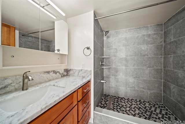 full bathroom featuring tiled shower and vanity