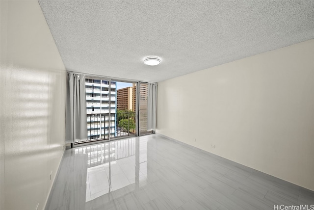 unfurnished room with expansive windows, baseboards, and a textured ceiling