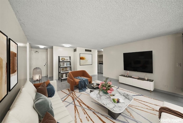 living area with visible vents, a textured ceiling, and washer and clothes dryer