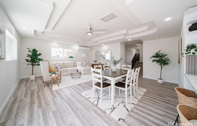 dining room with a tray ceiling, baseboards, visible vents, and a wall mounted air conditioner