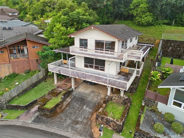 back of property with a garage, concrete driveway, a balcony, and fence