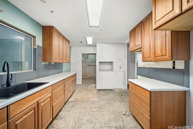 kitchen with light countertops, brown cabinetry, and a sink