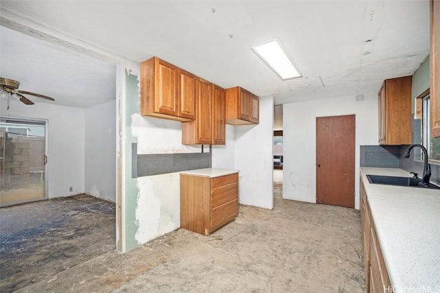 kitchen featuring brown cabinetry, light countertops, ceiling fan, and a sink