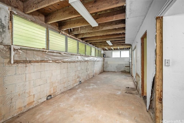 misc room with unfinished concrete floors and concrete block wall