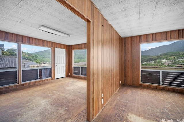 unfurnished room featuring a mountain view, plenty of natural light, and wooden walls