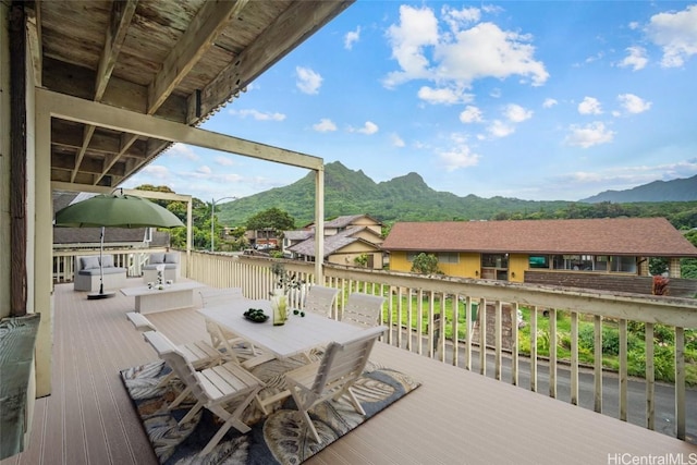 wooden terrace featuring a mountain view and outdoor dining space