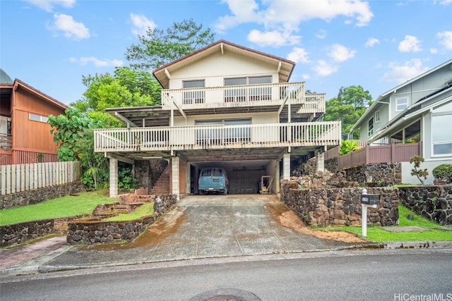 view of front of house with a wooden deck, a carport, concrete driveway, and fence