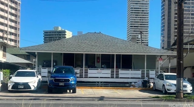 view of front facade with a shingled roof and a view of city