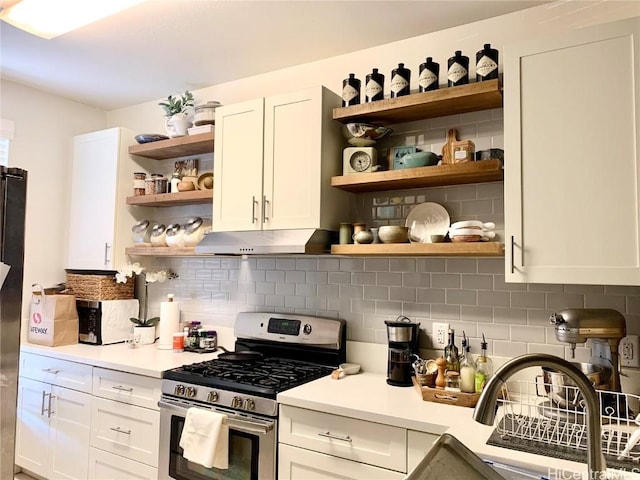 kitchen with under cabinet range hood, white cabinetry, light countertops, appliances with stainless steel finishes, and open shelves