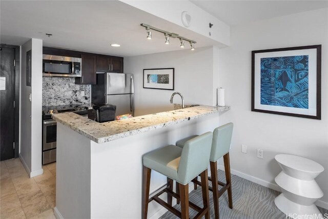 1777 Ala Moana Blvd Unit 2208, Honolulu, HI 96815 - kitchen featuring light stone counters, a breakfast bar, stainless steel appliances, backsplash, and a peninsula