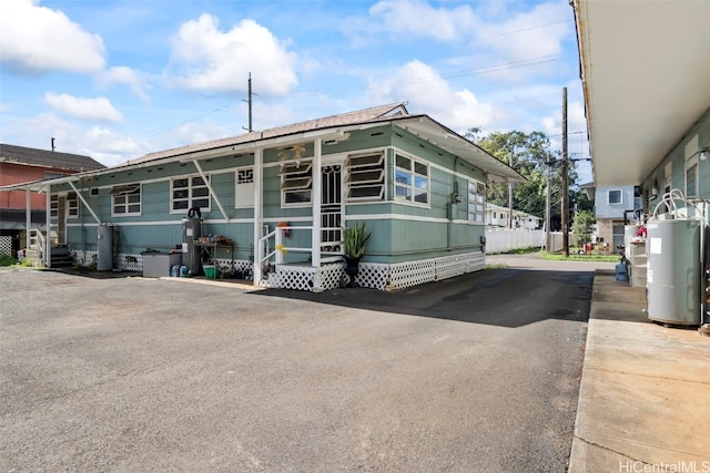 view of front of house featuring water heater and fence