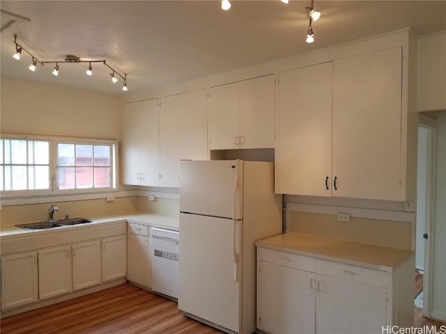 kitchen featuring light wood finished floors, light countertops, white cabinets, a sink, and white appliances