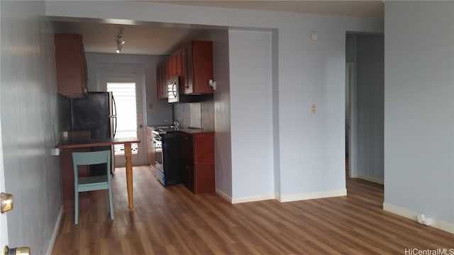 kitchen with baseboards, appliances with stainless steel finishes, decorative backsplash, and dark wood-type flooring