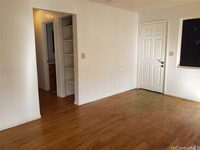 unfurnished room featuring dark wood-style flooring and baseboards