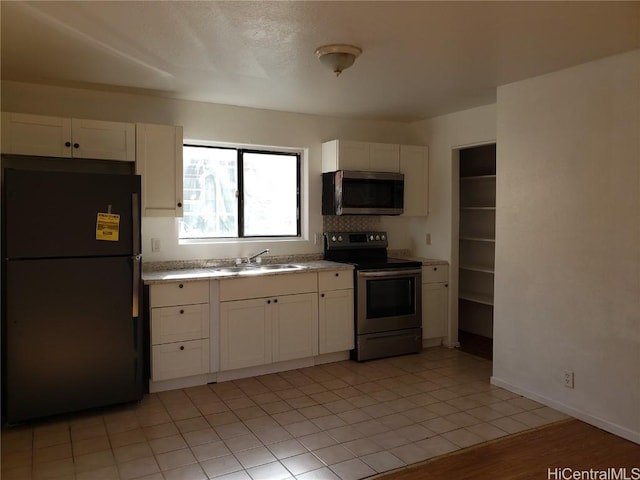 kitchen featuring stainless steel appliances, white cabinets, light countertops, and a sink