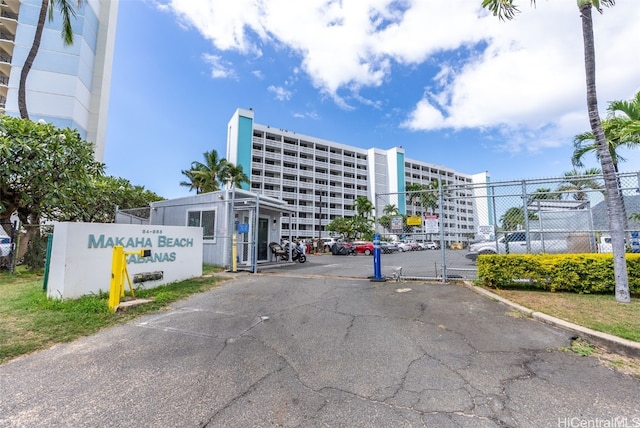 view of building exterior with uncovered parking and fence