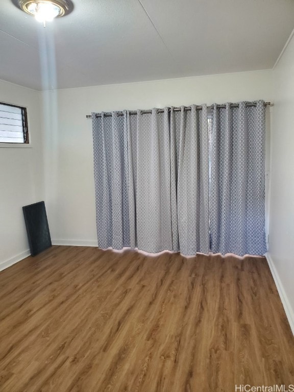 spare room featuring dark wood-style flooring and baseboards