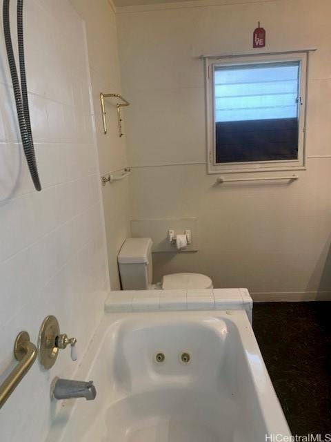 bathroom featuring a jetted tub and toilet