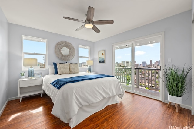 bedroom with a view of city, access to outside, baseboards, and wood finished floors