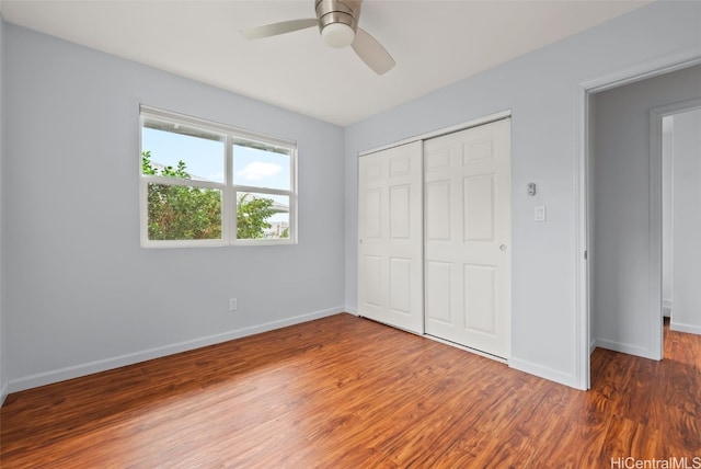 unfurnished bedroom with dark wood-style floors, ceiling fan, a closet, and baseboards