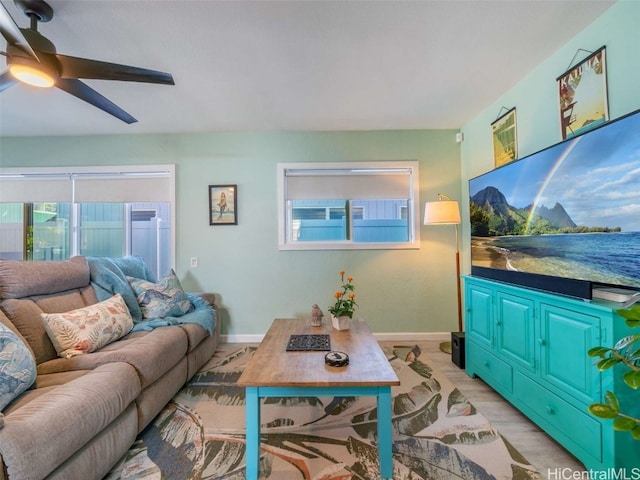 living area featuring baseboards, ceiling fan, and light wood-style floors