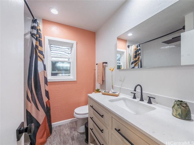 bathroom featuring toilet, plenty of natural light, baseboards, and vanity