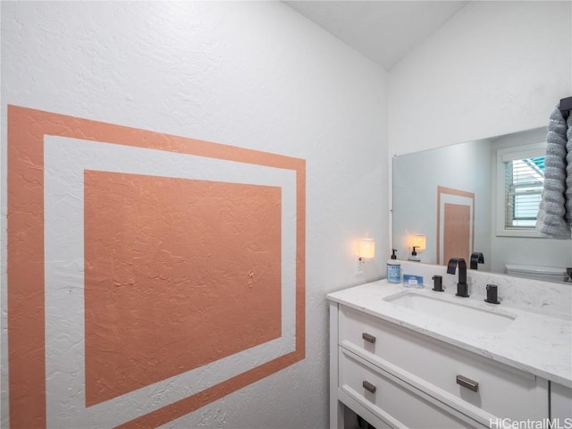 bathroom featuring vaulted ceiling, vanity, and toilet