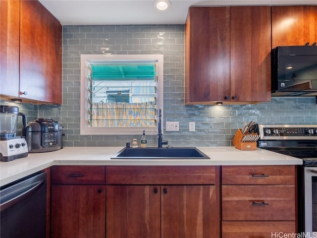 kitchen with backsplash, appliances with stainless steel finishes, light countertops, and a sink