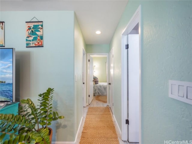 hallway with recessed lighting and baseboards