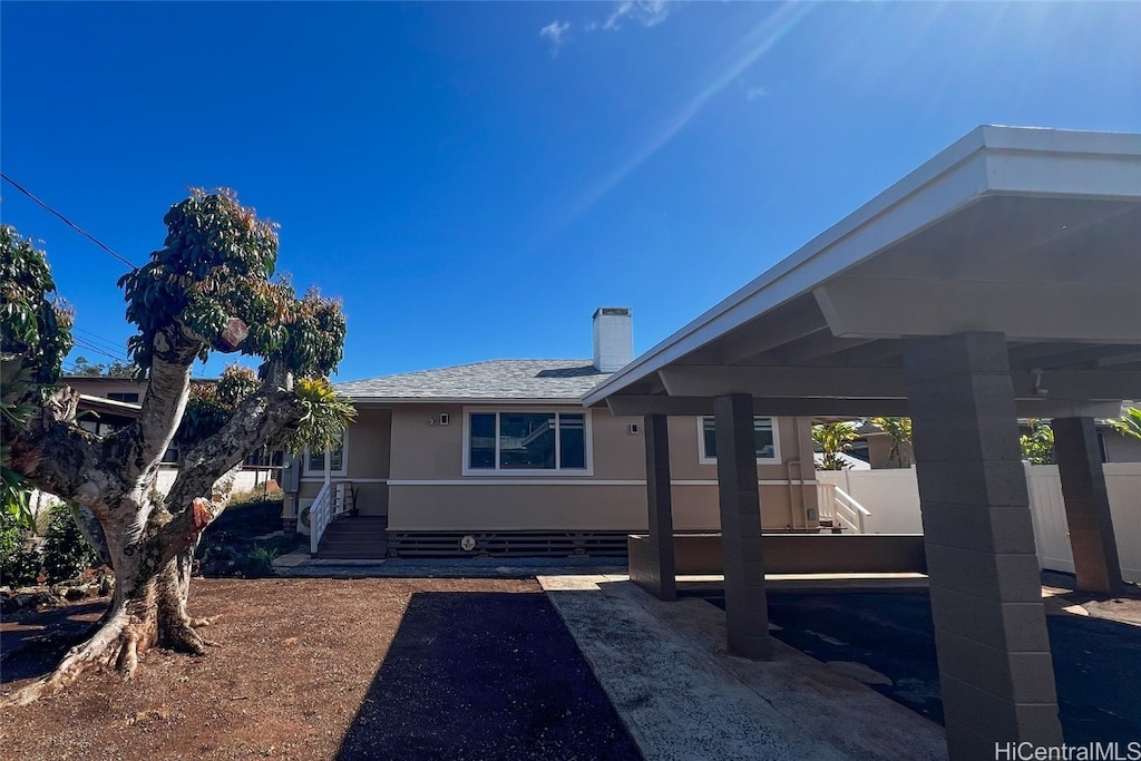 back of property with a shingled roof, a chimney, and stucco siding