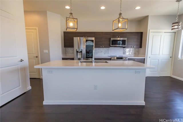 kitchen featuring stainless steel appliances, light countertops, dark brown cabinetry, and a center island with sink