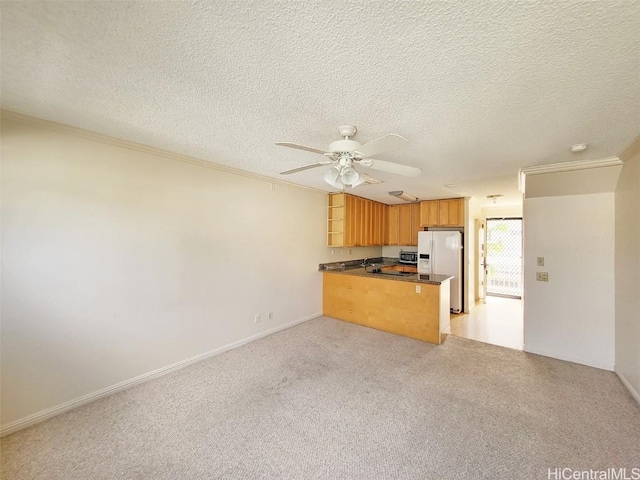 kitchen featuring a peninsula, open floor plan, ornamental molding, white fridge with ice dispenser, and dark countertops