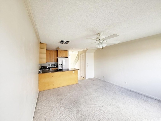 kitchen with dark countertops, visible vents, ceiling fan, refrigerator with ice dispenser, and a textured ceiling