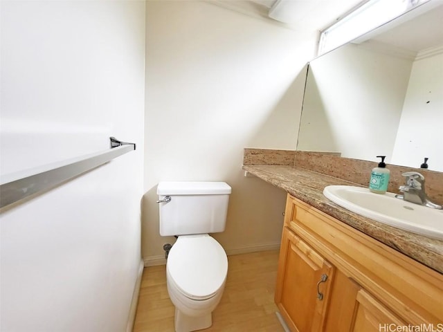 half bathroom featuring toilet, wood finished floors, vanity, and baseboards