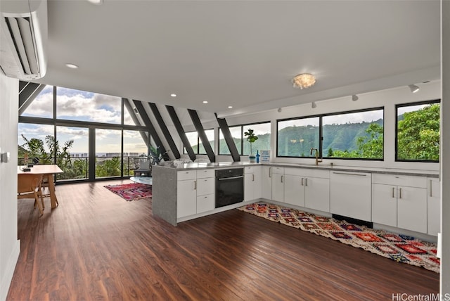 kitchen featuring white cabinets, black oven, white dishwasher, and a peninsula