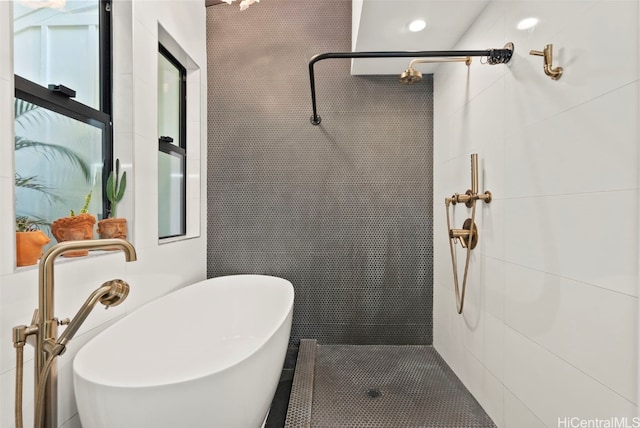 full bathroom with a stall shower, a sink, and tile walls