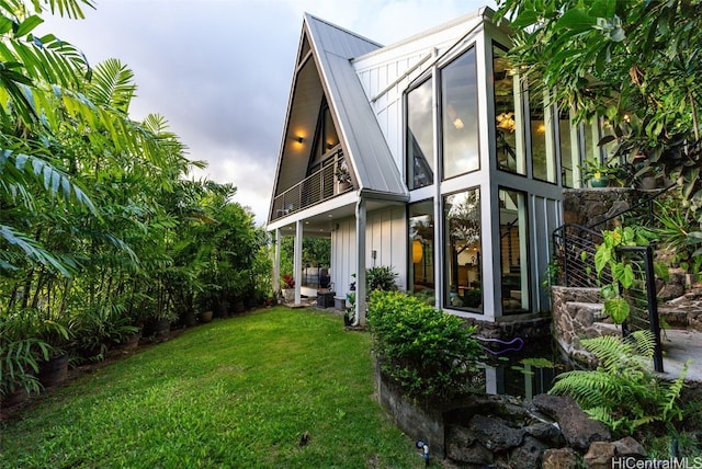 view of side of property featuring metal roof, a yard, board and batten siding, and a balcony