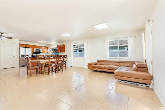 living area with light tile patterned flooring, a ceiling fan, and baseboards