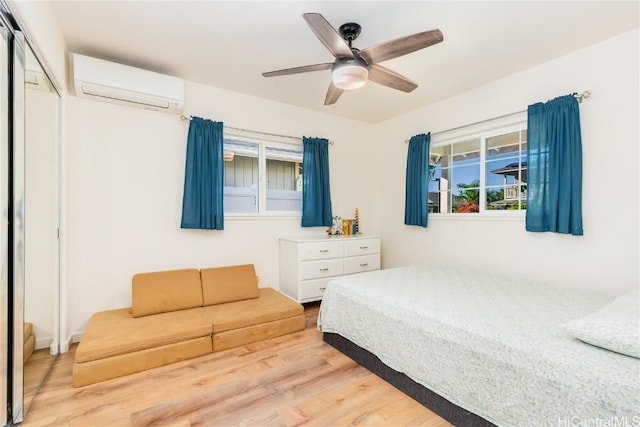 bedroom featuring ceiling fan, light wood finished floors, a wall mounted AC, and a closet